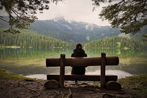 Young woman sitting on a bench looking across the Black Lake Crno jezero in Durmitor National Park, Zabljak, Montenegro, Western Balkan, Europe